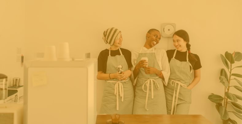 How an employee check-in reduces frontline employee challenges | Weekly10 blog | Three female cafe employees are chatting and drinking coffee.