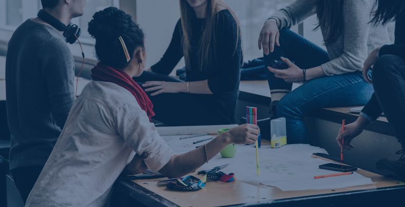 The benefits of workplace resilience | Blog | A group of colleagues sat around a table chatting.